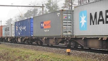 Goederentrein met zeecontainers die langs het spoor voorbijkomt