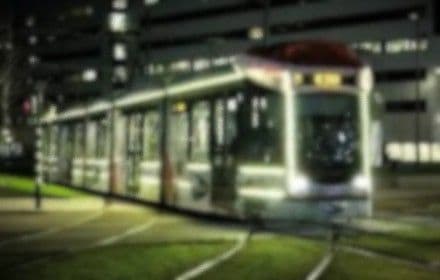 Verlichte tram in de nacht op een grasbaan in Rotterdam